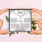 personalized cross on snake chain in a soft box in model's hands