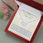 A everlasting love necklace in a mahogany box on a table angled to the left.
