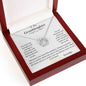 A white gold lucky in love necklace up close in a mahogany box angled to left