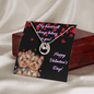 lucky in love necklace on a greeting card leaning on a closed mahogany box birds eye view