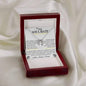 a lucky in love necklace up close in a mahogany box on a white cloth.