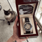 openwork watch in a mahogany box in a model's hand with a cat