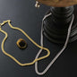 yellow gold and stainless-steel Cuban link chain on a black table