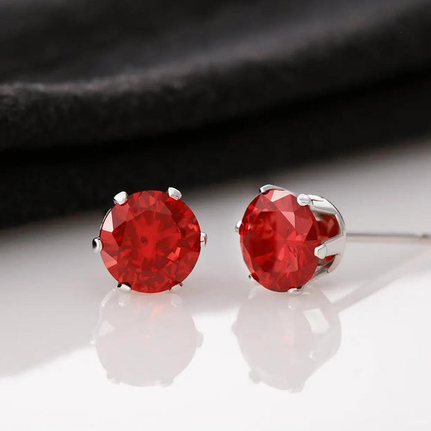 Red Cubic Zirconia Earrings on a white table with a black cloth behind the earrings