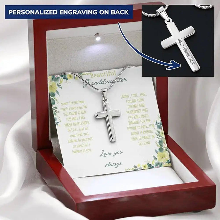 Personalized Cross Necklace with a polished stainless-steel cross and a to granddaughter greeting card in a mahogany box on a white cloth backdrop angled slightly right
