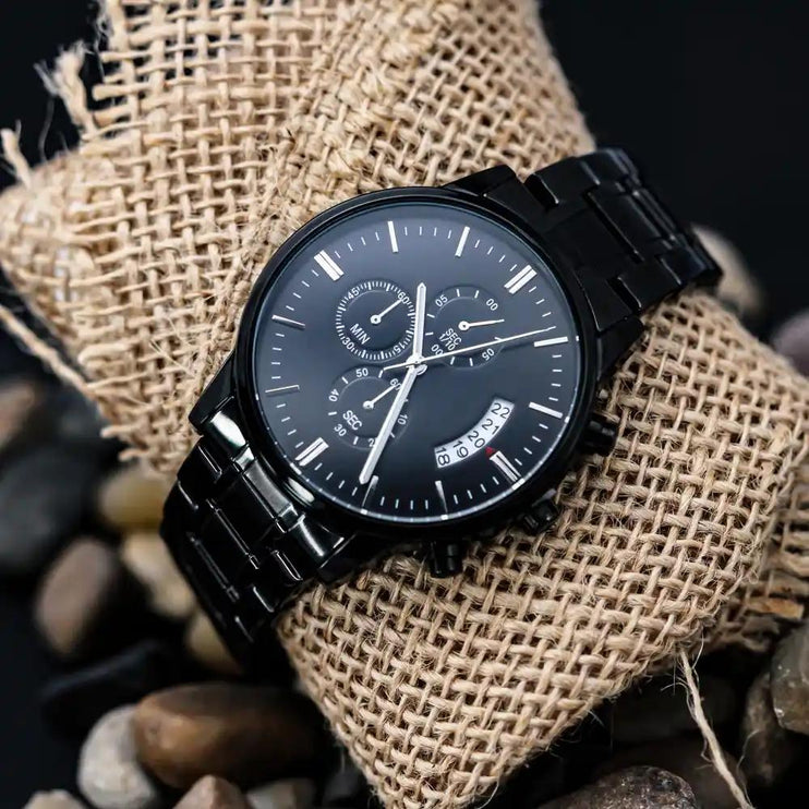 a black chronograph watch on a burlap bag.