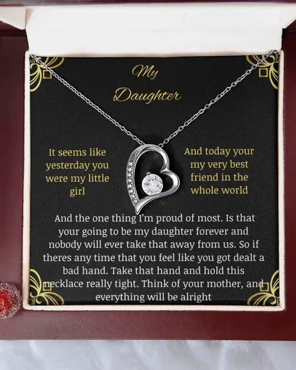 Forever Love Necklace with a white gold charm in a mahogany box with a to daughter from mom greeting card on a white table looking down