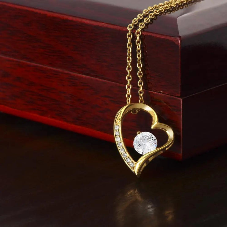 yellow gold forever love necklace on a mahogany box 