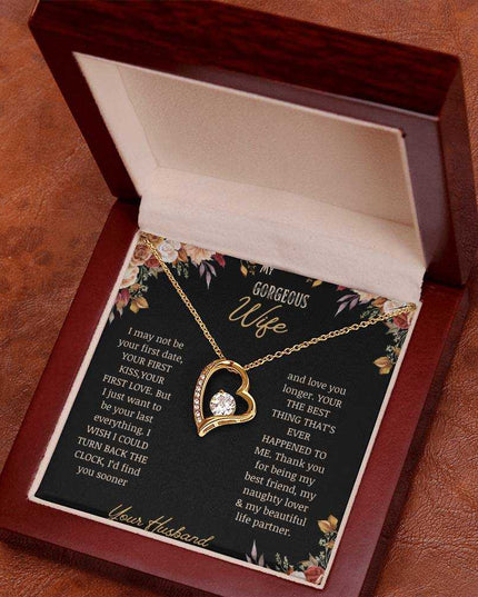A yellow gold Forever Love Necklace on a to wife greeting card in a mahogany box on a table.