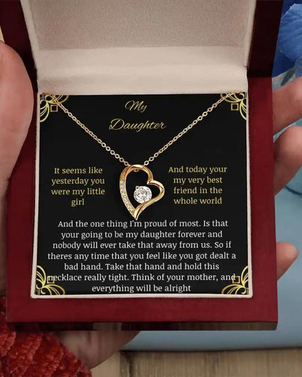 Forever Love Necklace with a yellow gold charm in a mahogany box with a to daughter from mom greeting card angle straight close up in models hand