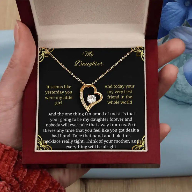 Forever Love Necklace with a yellow gold charm in a mahogany box with a to daughter from mom greeting card angle straight close up in models hand