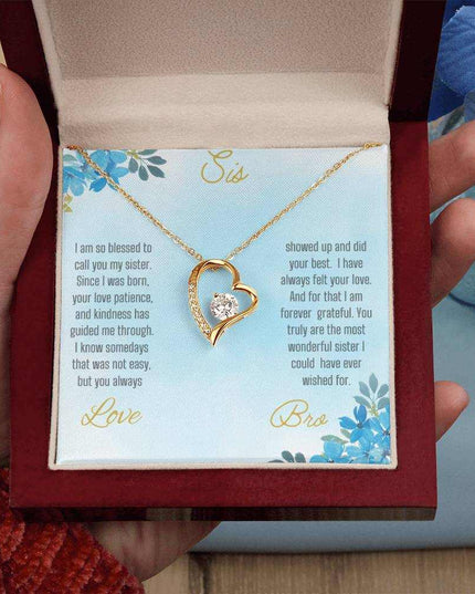 Forever Love Necklace with a yellow gold variant on a to sis from bro greeting card close up view in a mahogany box in a models hand.