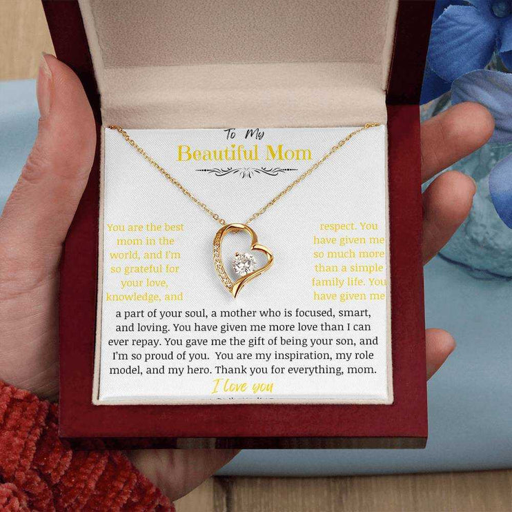 A yellow gold forever love necklace in a mahogany box in a models hand