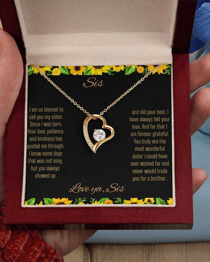 Forever Love Necklace with a yellow gold charm on a To Sis from Sis greeting card up close in a mahogany box in a models hand