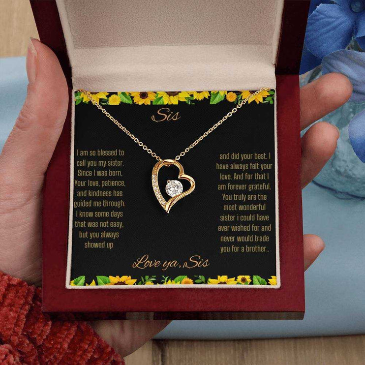 Forever Love Necklace with a yellow gold charm on a To Sis from Sis greeting card up close in a mahogany box in a models hand
