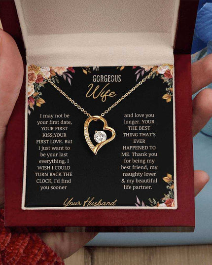 A yellow gold Forever Love Necklace on a to wife greeting card in a mahogany box in a models hand.