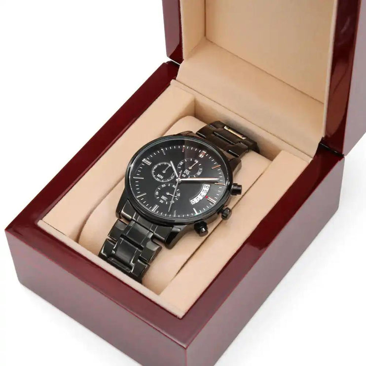 a black chronograph watch in a mahogany box angled right