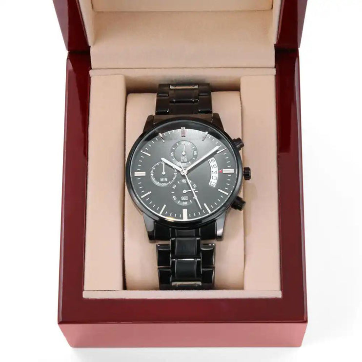 a black chronograph watch in a mahogany box up close