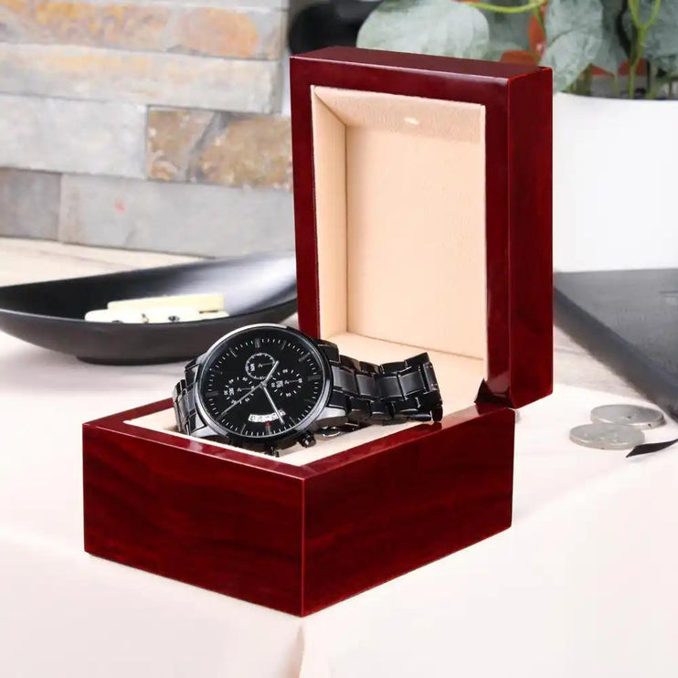 a black chronograph watch in a mahogany box angled right with open lid