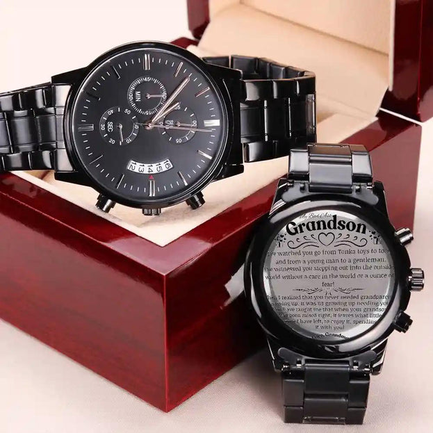 a black chronograph watch in a mahogany box