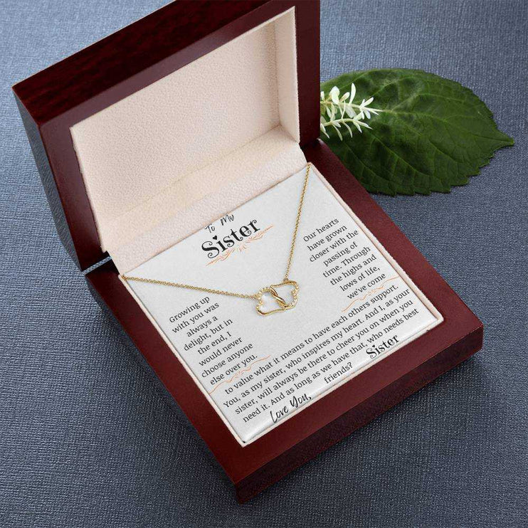 a 10k everlasting love necklace in a mahogany box on a table angled left