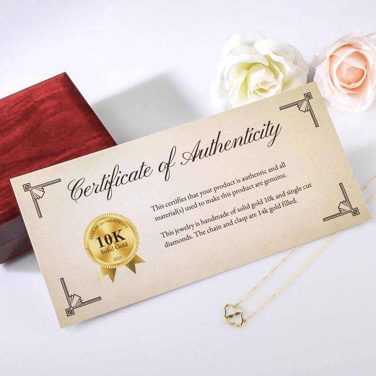 A certificate of authenticity leaning on a mahogany box and white and pink rose sitting on a white table top close up view