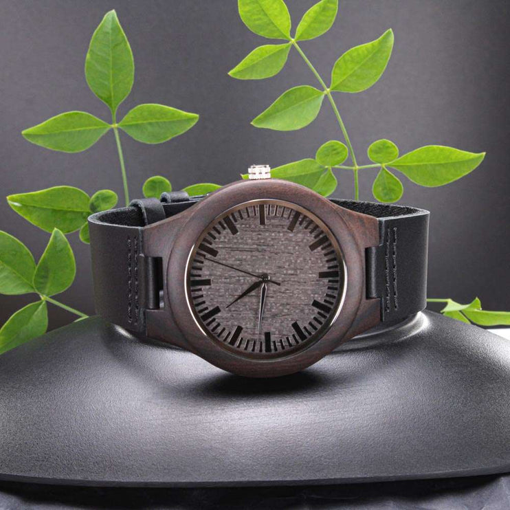 wooden watch engraved on a black seat with plants