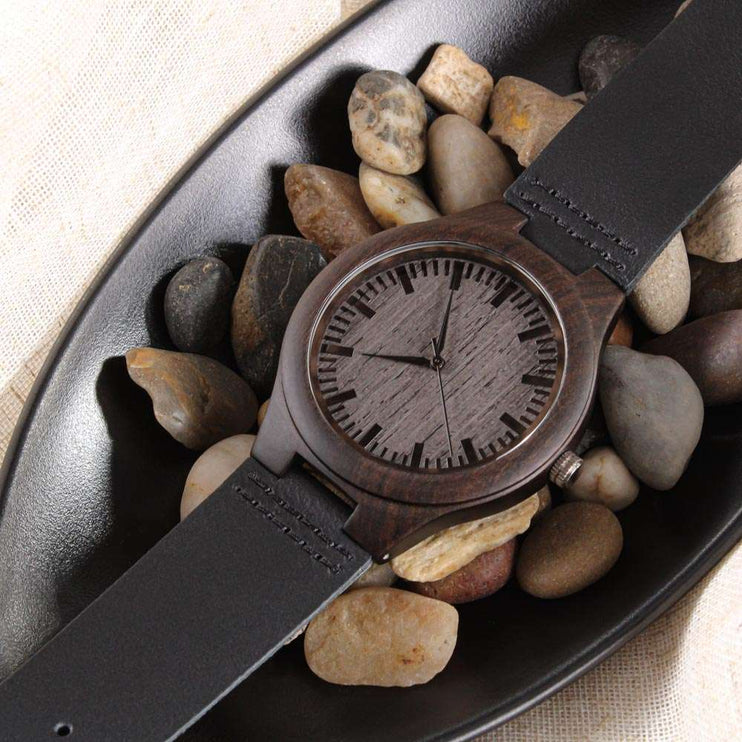 wooden watch engraved in a bed of pebbles