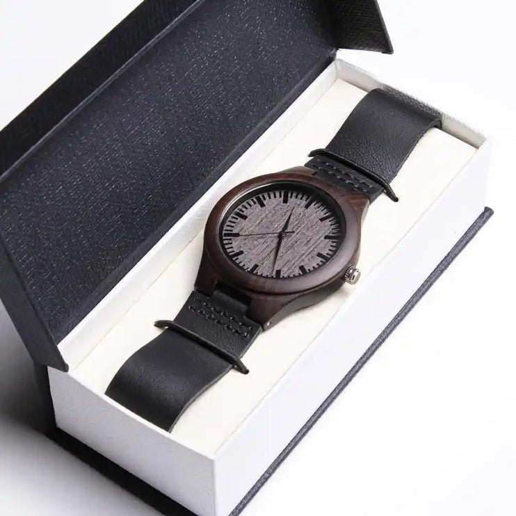 A engraved wooden watch face up in a two-tone box