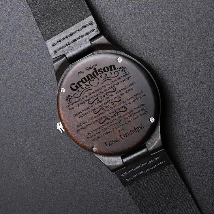 A engraved wooden watch face down showing message on back on a black background