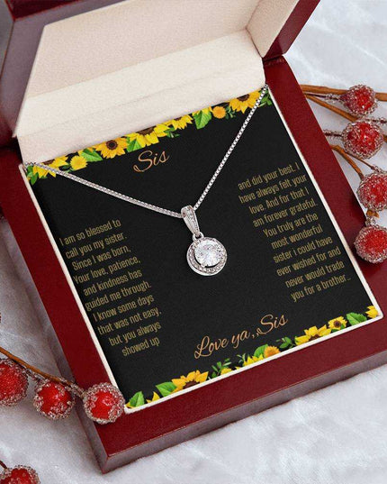 Eternal Hope Necklace on a To Sis from Sis greeting card in a mahogany box angled to the right sitting on a white table cloth with red flower bud stemsclose up view.