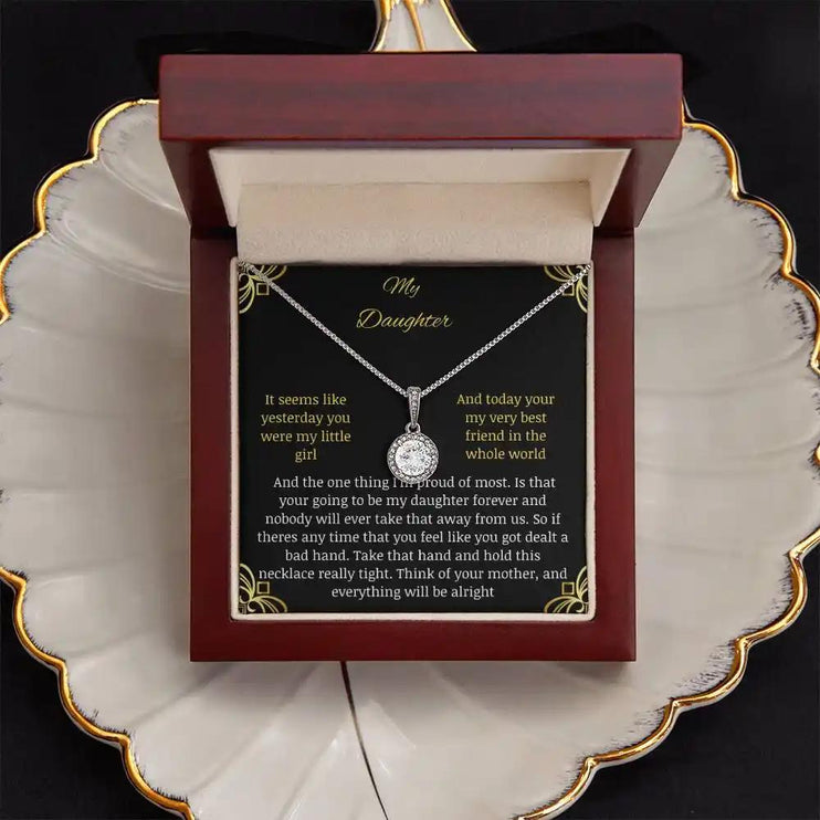 Eternal Hope Necklace in a mahogany box with a to daughter from mom greeting card sitting on a coffee filter looking straight down