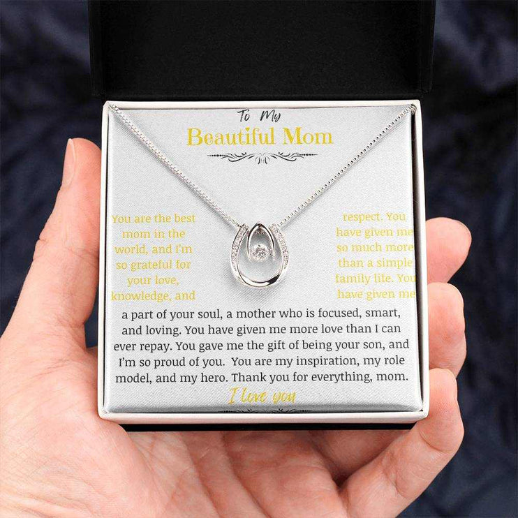 A lucky in love necklace in a two-tone box in a models hand