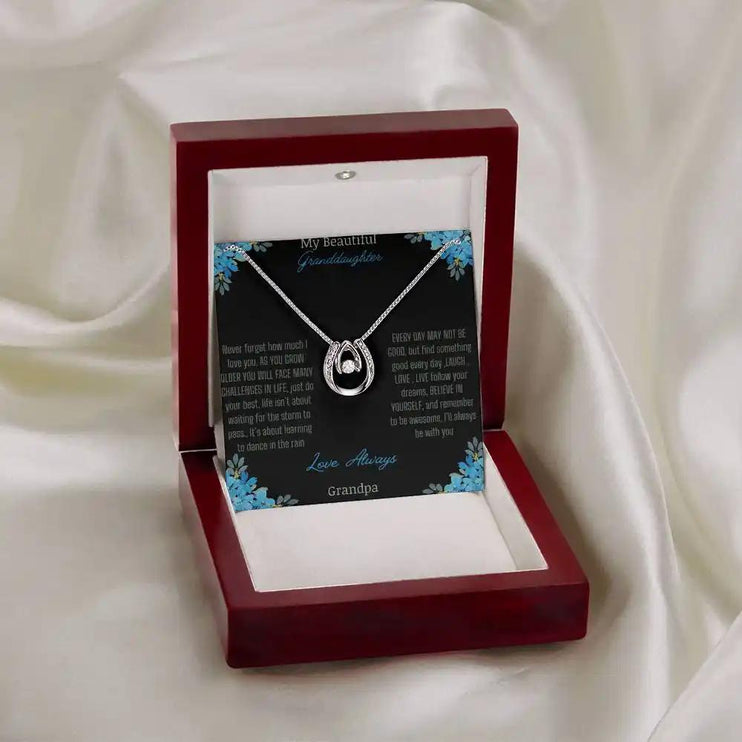 Lucky In Love Necklace with a white gold charm on a to granddaughter from grandpa greeting card in a mahogany box angled to the right on a white drop cloth