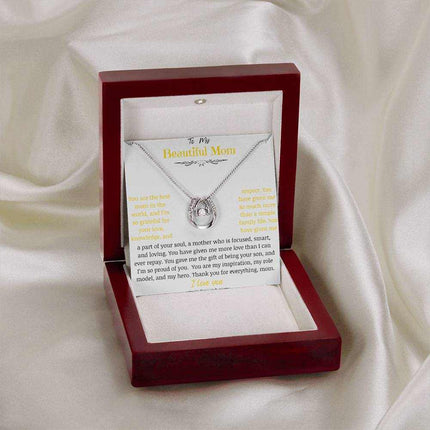 A lucky in love necklace in a mahogany box on a white cloth
