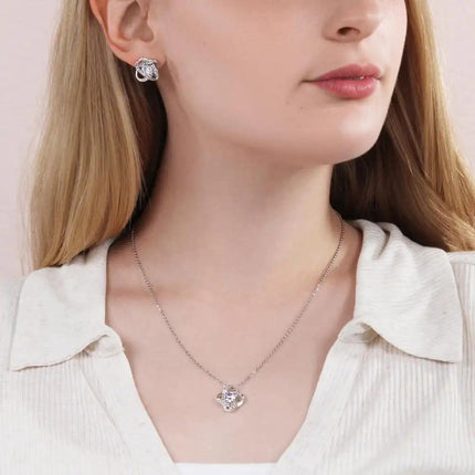 a white gold love knot necklace on a model.