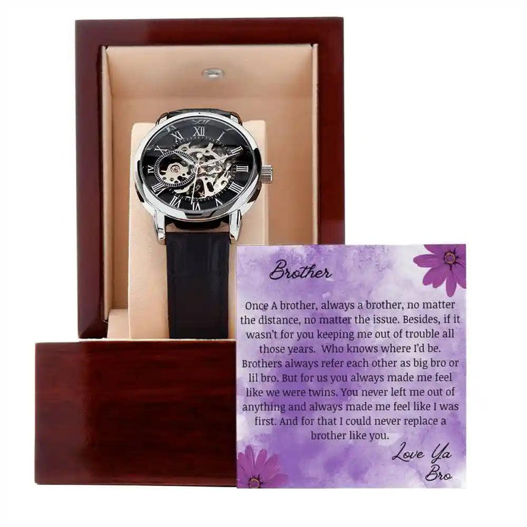 A men's openwork watch and a to brother greeting card in a mahogany box up close.
