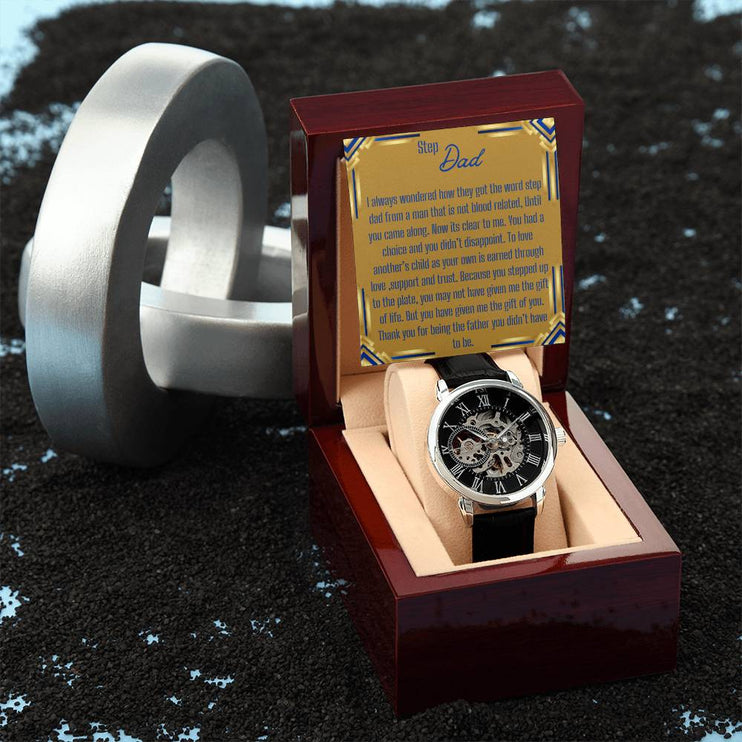 a men's openwork watch in a mahogany box with to stepdad greeting next to a silver decoration.
