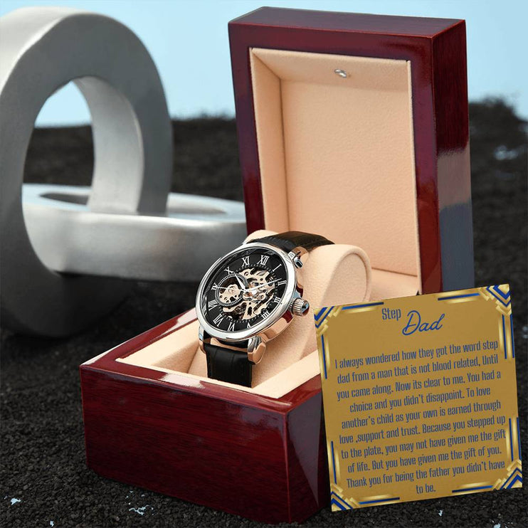a men's openwork watch in a mahogany box with to stepdad greeting card angled to the right.