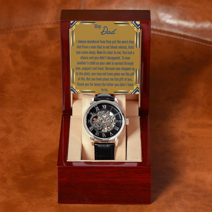 a men's openwork watch in a mahogany box with to stepdad greeting on a rustic table.