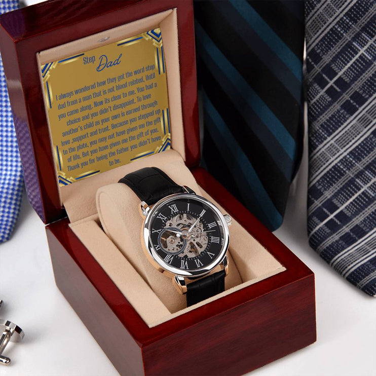 a men's openwork watch in a mahogany box with to stepdad greeting on a nightstand.