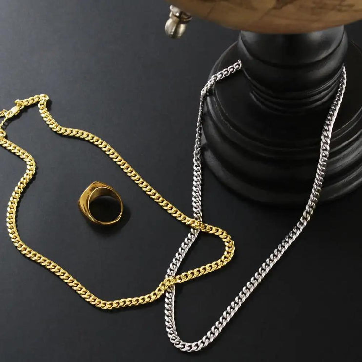 gold and polished steel cuban link chain on black table