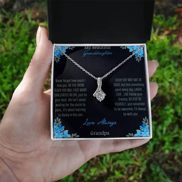 Alluring Beauty Necklace with a white gold charm with a to granddaughter from grandpa greeting card in a two-tone box in a models hand
