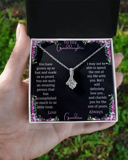 Alluring Beauty Necklace with a white gold charm with a to granddaughter from grandma greeting card in a two-tone box in a models hand
