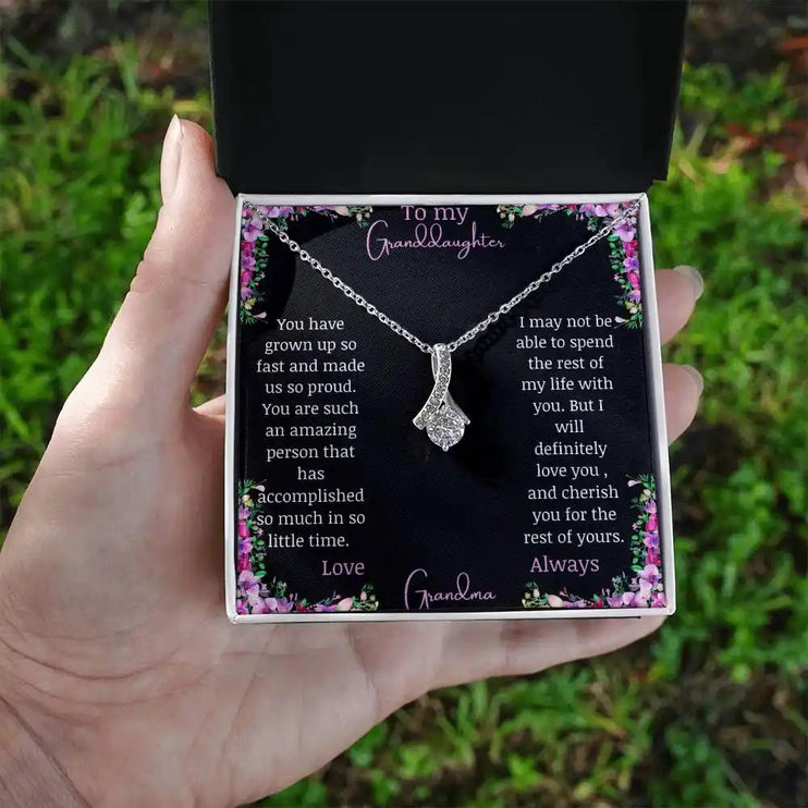 Alluring Beauty Necklace with a white gold charm with a to granddaughter from grandma greeting card in a two-tone box in a models hand