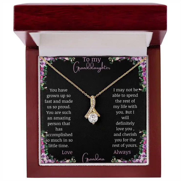 Alluring Beauty Necklace with a yellow gold charm with a to granddaughter from grandma greeting card up close in a mahogany box