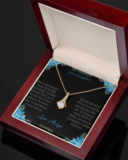 Alluring Beauty Necklace with a yellow gold charm with a to granddaughter from grandpa greeting card in a mahogany box angled to the left side