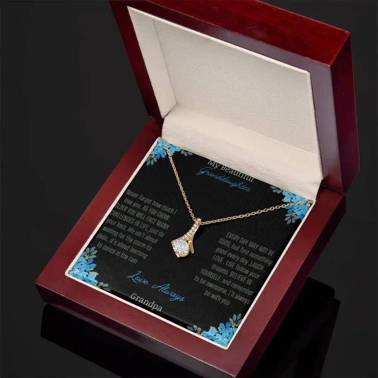 Alluring Beauty Necklace with a yellow gold charm with a to granddaughter from grandpa greeting card in a mahogany box angled to the left side