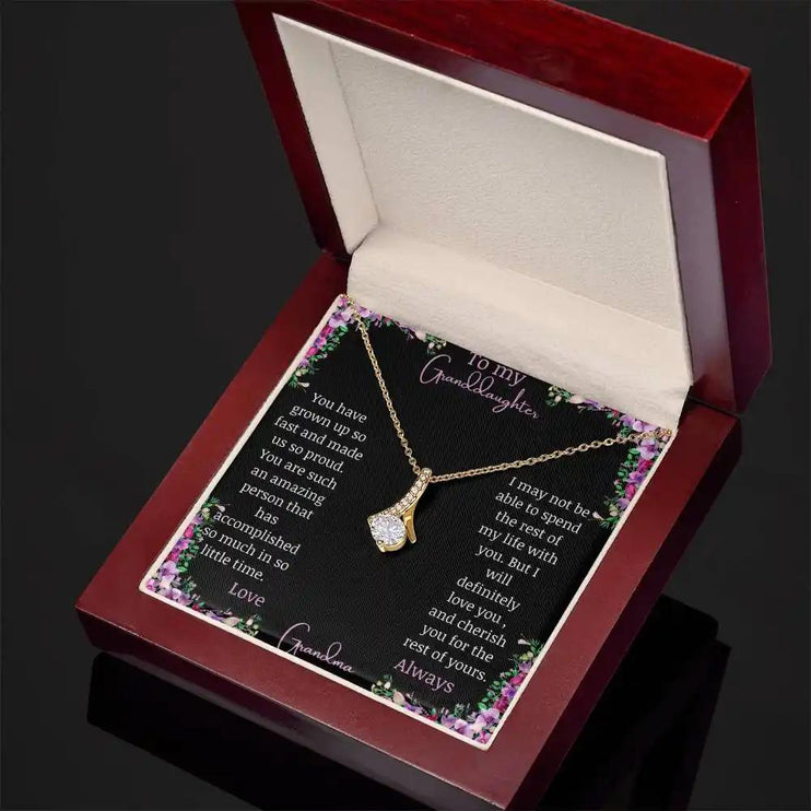 Alluring Beauty Necklace with a yellow gold charm with a to granddaughter from grandma greeting card up close in a mahogany box angled to the right side