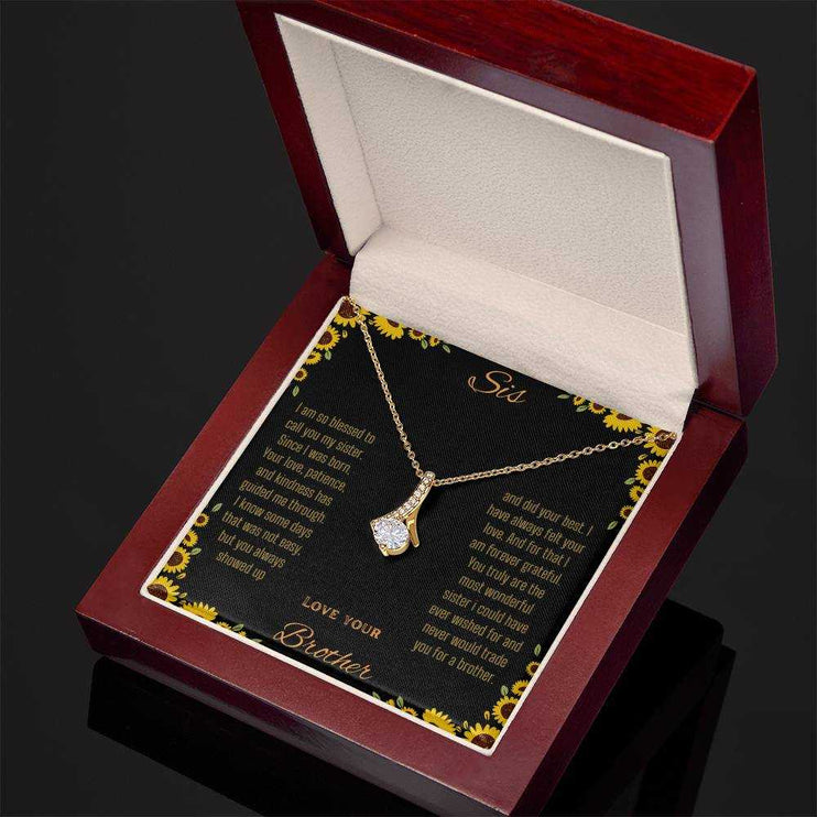 Alluring Beauty Necklace with a yellow gold variant on a To Sis from Brother greeting card inside a mahogany box angled slightly to the right close up view
